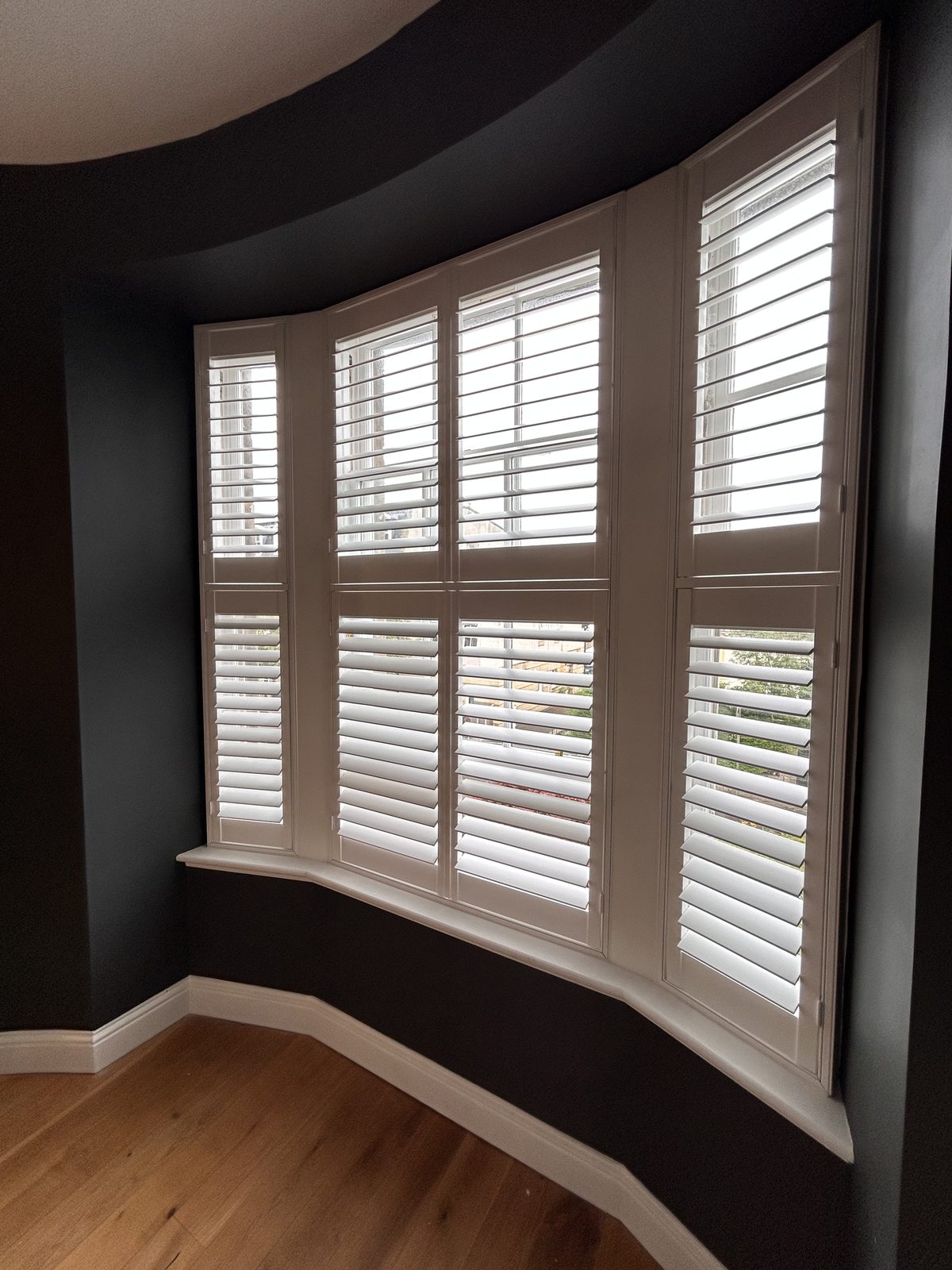 Wooden shutters fitted to a bay window